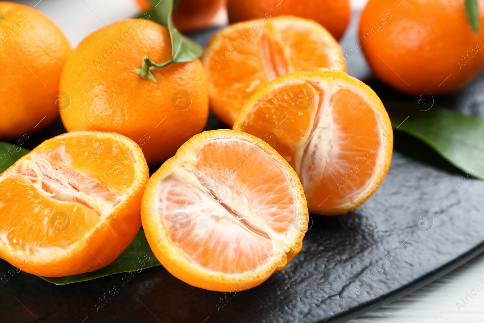 Photo of Delicious fresh tangerines on slate board, closeup