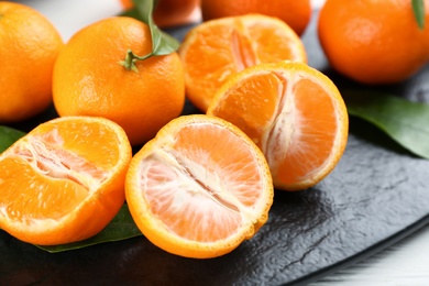 Photo of Delicious fresh tangerines on slate board, closeup