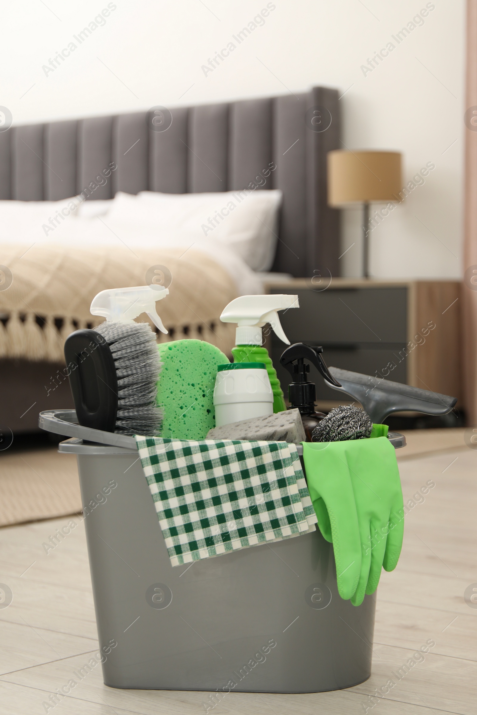 Photo of Different cleaning supplies in bucket on floor at home