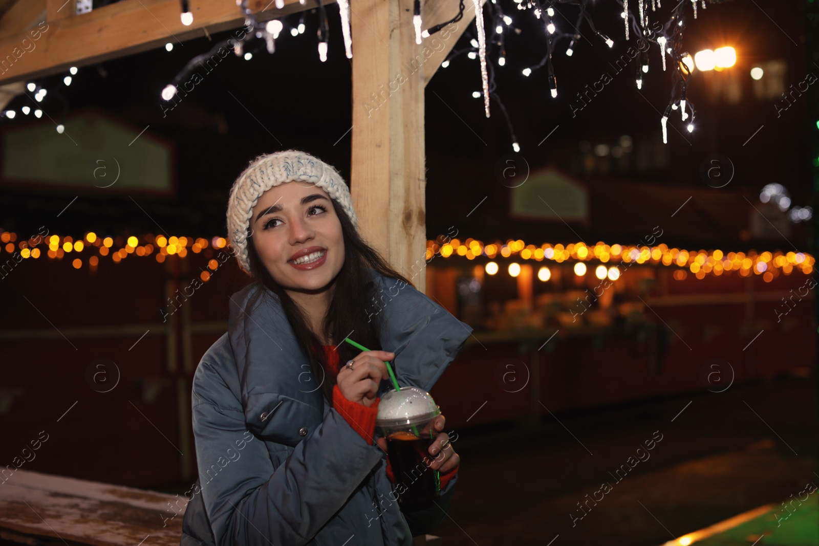 Photo of Woman with cup of mulled wine at winter fair. Space for text