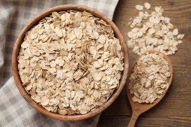Photo of Bowl and spoon with oatmeal on wooden table, flat lay