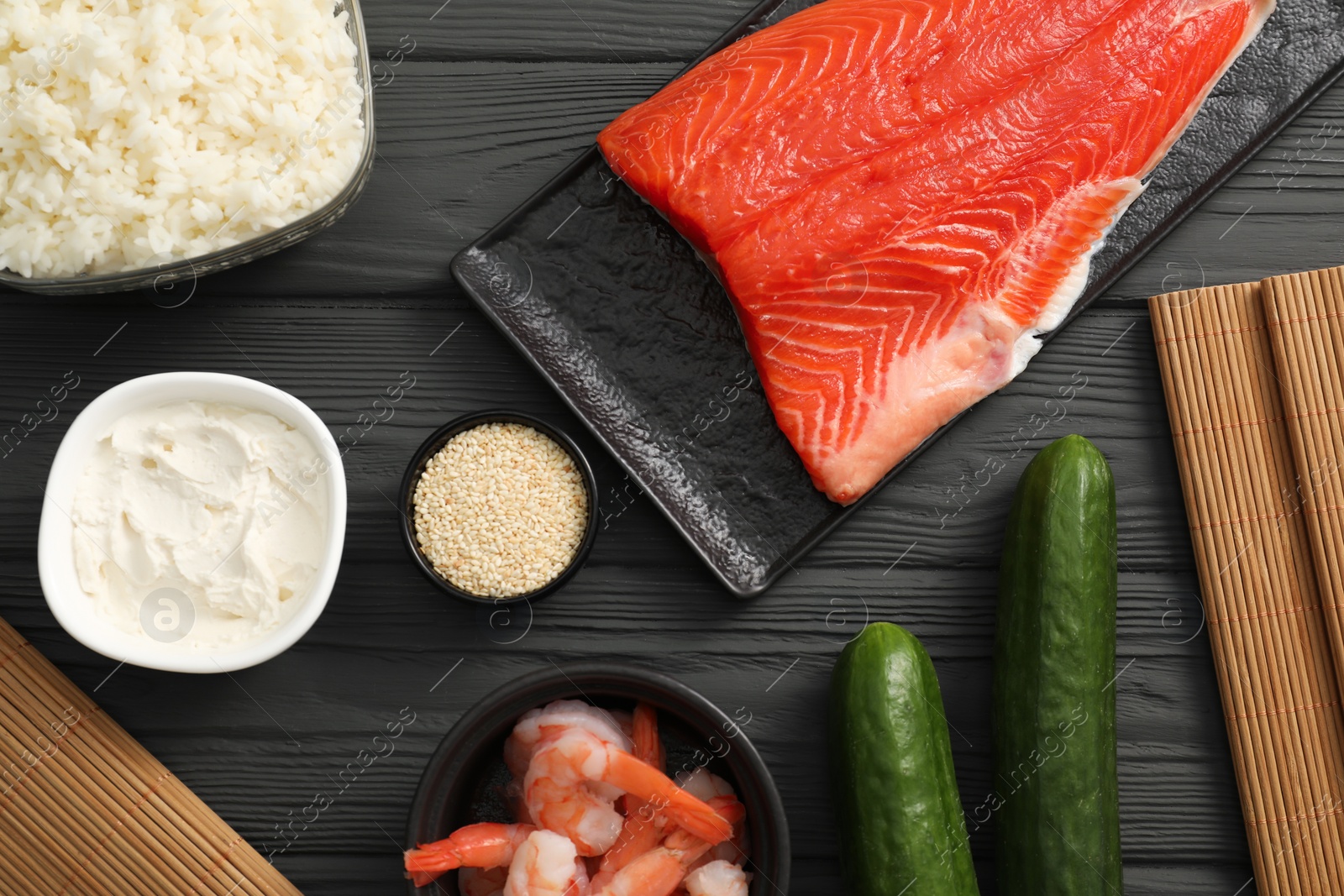 Photo of Making sushi rolls. Flat lay composition with ingredients on black wooden table