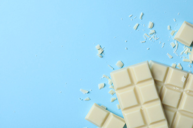 Photo of Tasty white chocolate on light blue background, flat lay. Space for text