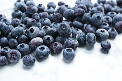 Photo of Tasty frozen blueberries on white marble table, closeup