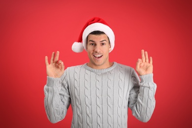 Photo of Emotional man wearing Santa hat on red background