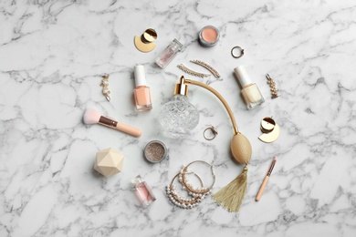 Flat lay composition with perfume bottles, jewelry and decorative cosmetics on white marble table