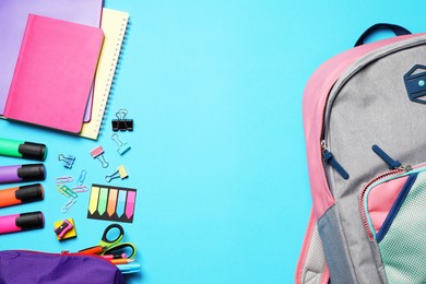 Photo of Flat lay composition with backpack and school stationery on light blue background, space for text