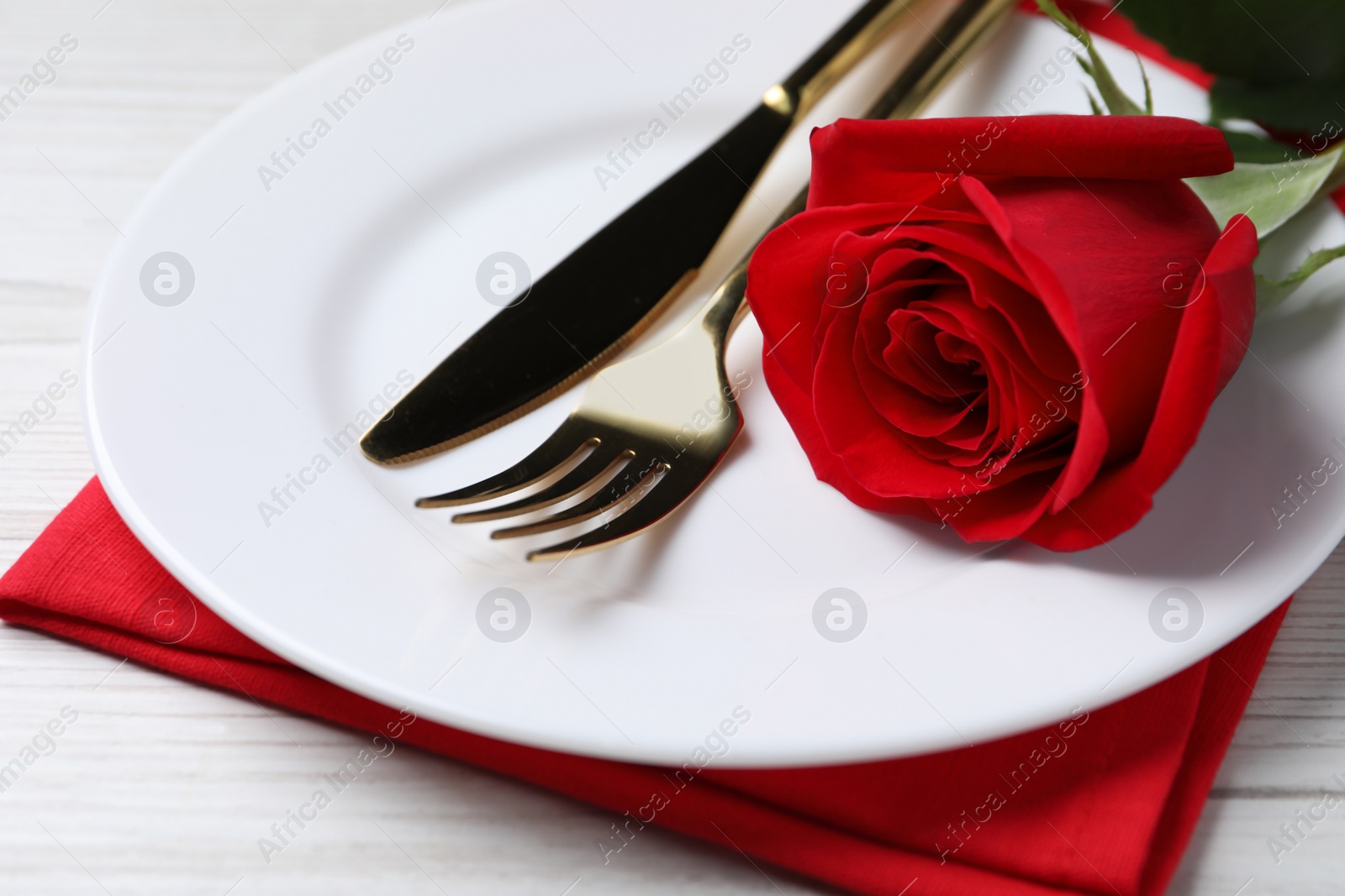 Photo of Beautiful place setting with dishware and rose for romantic dinner on white wooden table, closeup