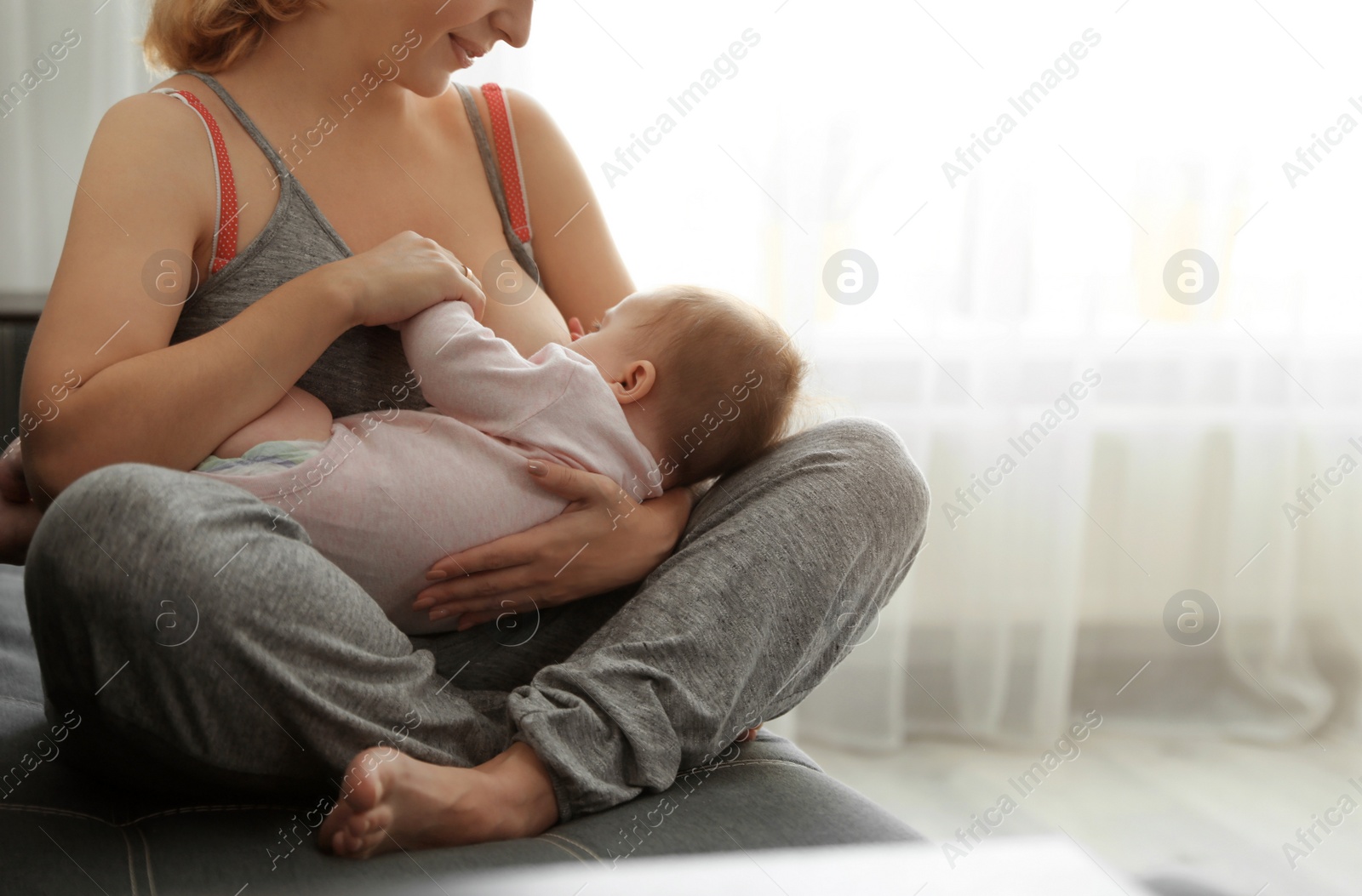 Photo of Young woman breastfeeding her baby at home