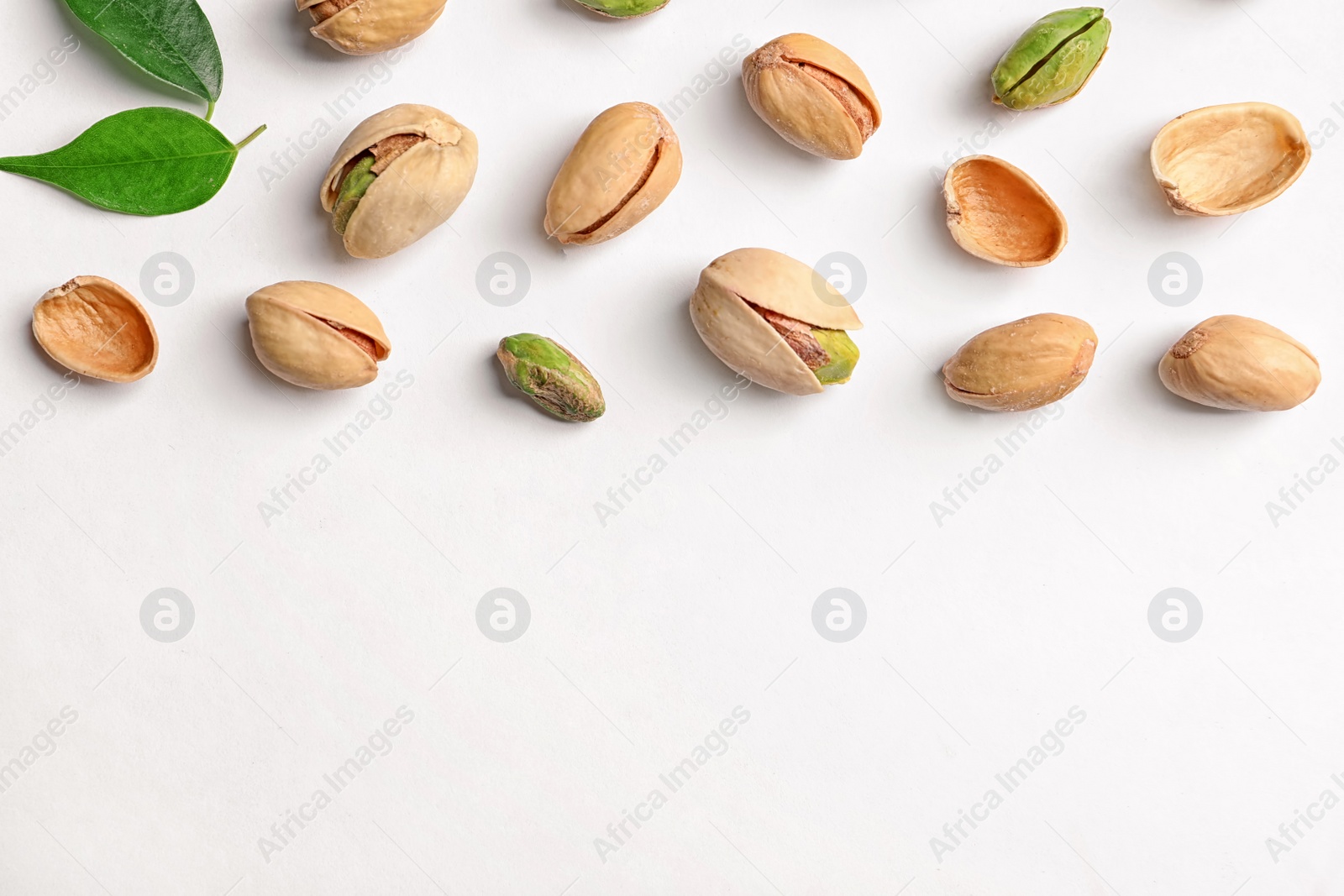 Photo of Organic pistachio nuts on white background, flat lay. Space for text