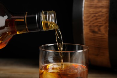 Photo of Pouring whiskey from bottle into glass, closeup