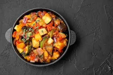 Photo of Dish with tasty ratatouille on black table, top view. Space for text