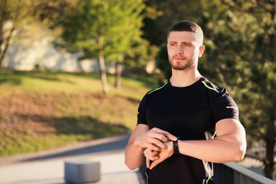 Photo of Attractive serious man checking pulse after training in park. Space for text