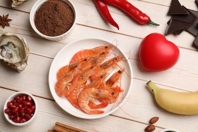 Photo of Natural aphrodisiac. Different food products and red decorative heart on light wooden table, flat lay