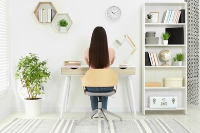 Photo of Home workplace. Woman working at comfortable desk in room, back view