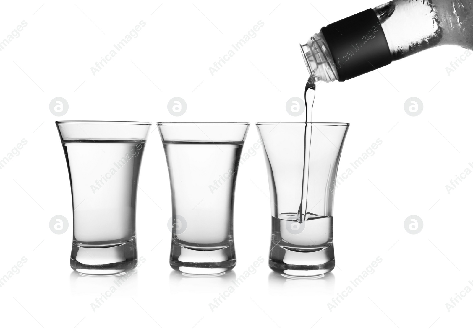 Photo of Pouring cold vodka into shot glass on white background