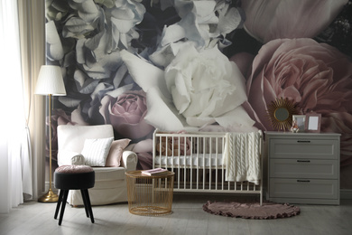 Baby room interior with stylish crib and floral wallpaper