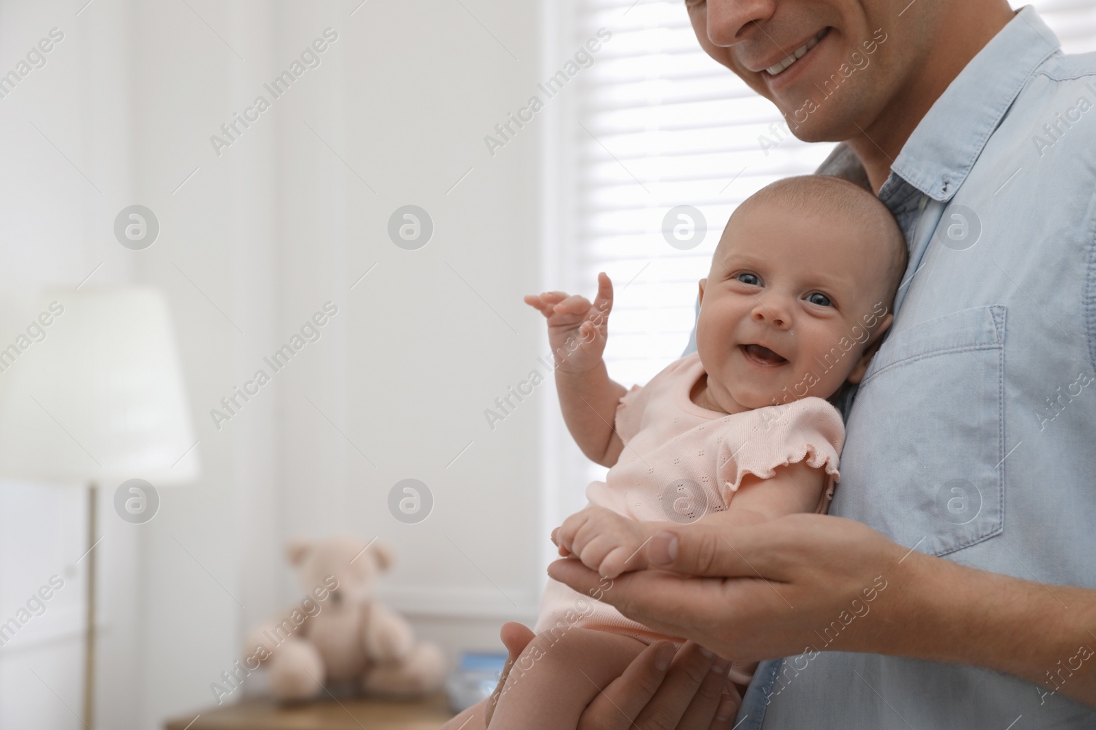 Photo of Happy father holding his cute little baby at home, closeup. Space for text