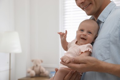 Photo of Happy father holding his cute little baby at home, closeup. Space for text