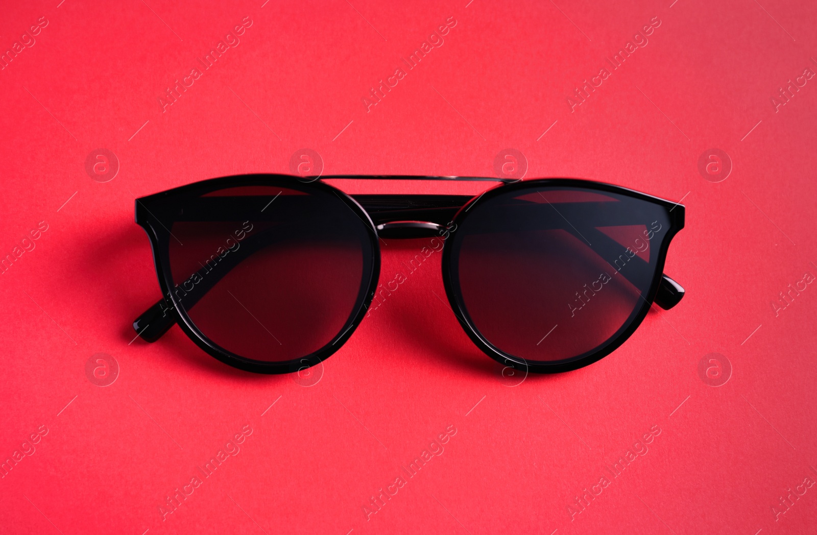 Photo of Stylish sunglasses on pink background, top view