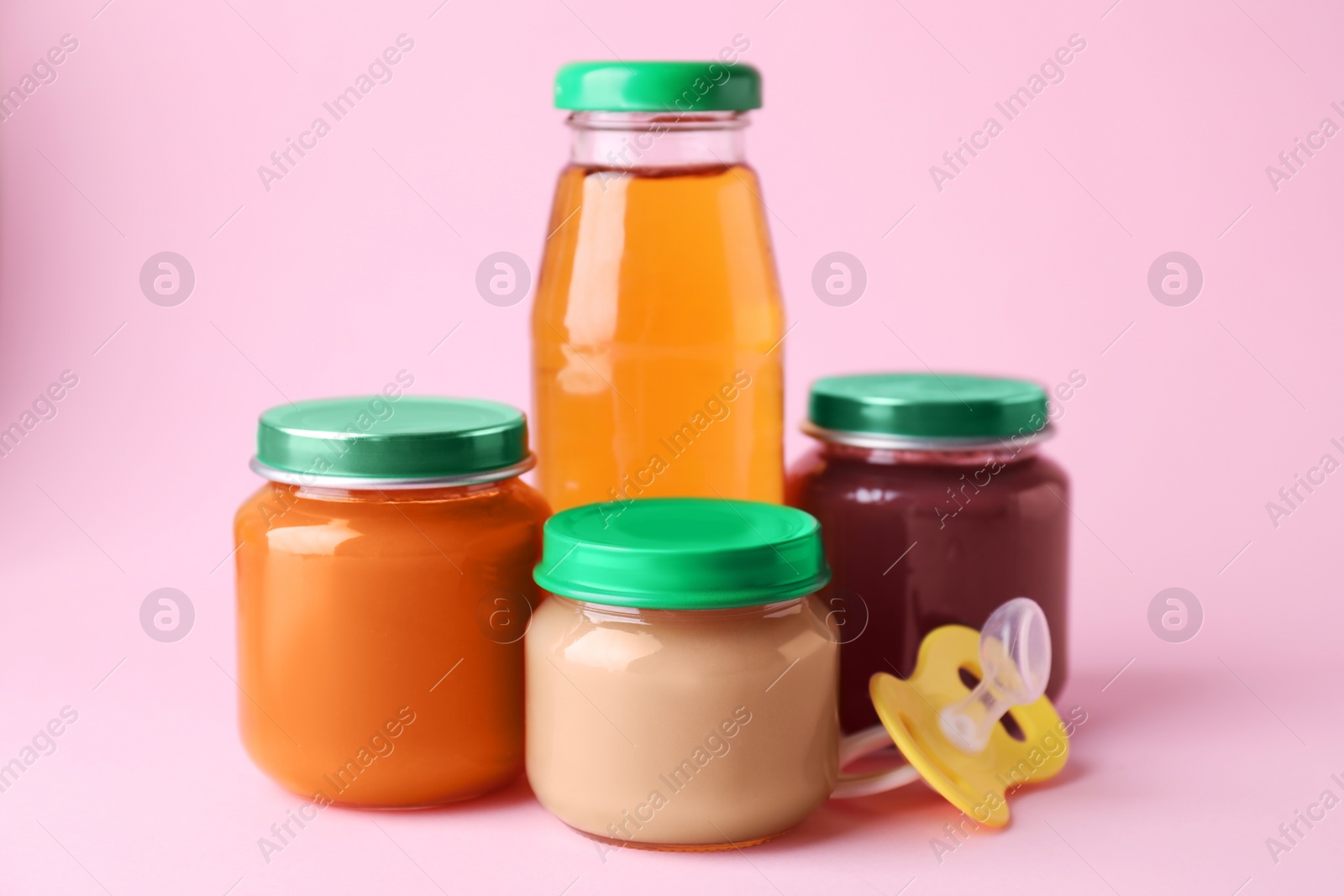 Photo of Healthy baby food, juice and pacifier on pink background