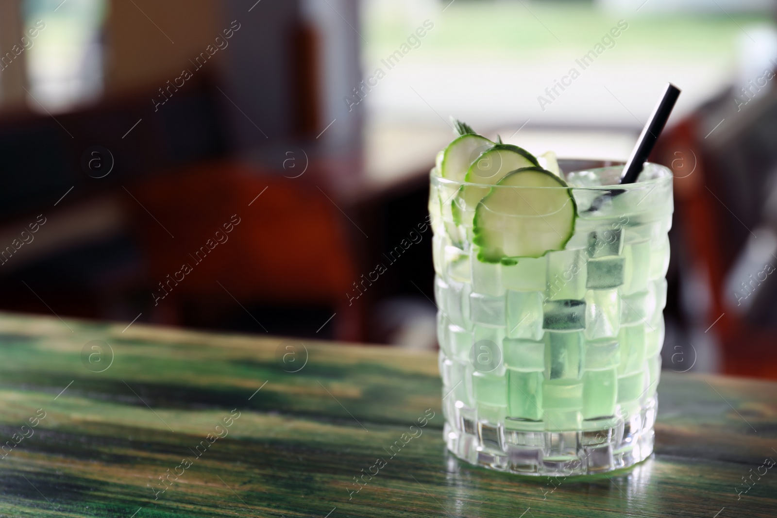 Photo of Glass of delicious cocktail with ice on table in bar