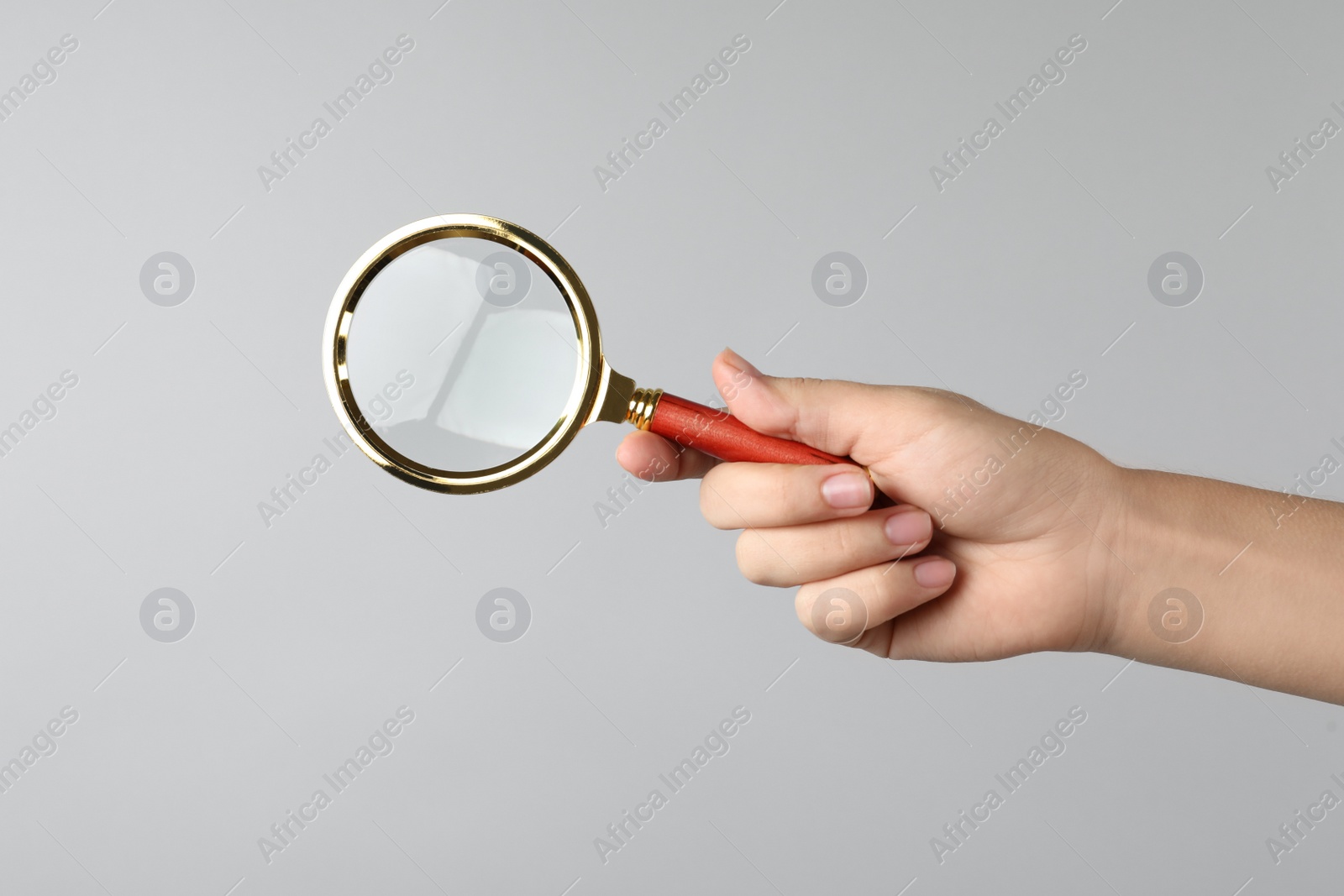 Photo of Woman holding magnifying glass on grey background, closeup. Find keywords concept