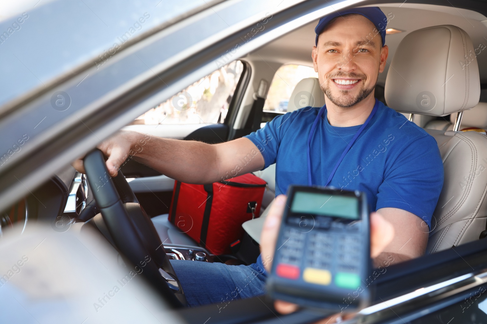 Photo of Male courier with terminal in car. Food delivery service