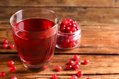 Photo of Tasty cranberry juice in glass and fresh berries on wooden table, closeup. Space for text
