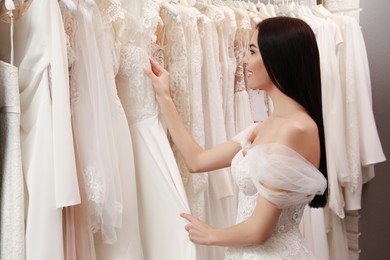 Photo of Young woman choosing wedding dress in salon