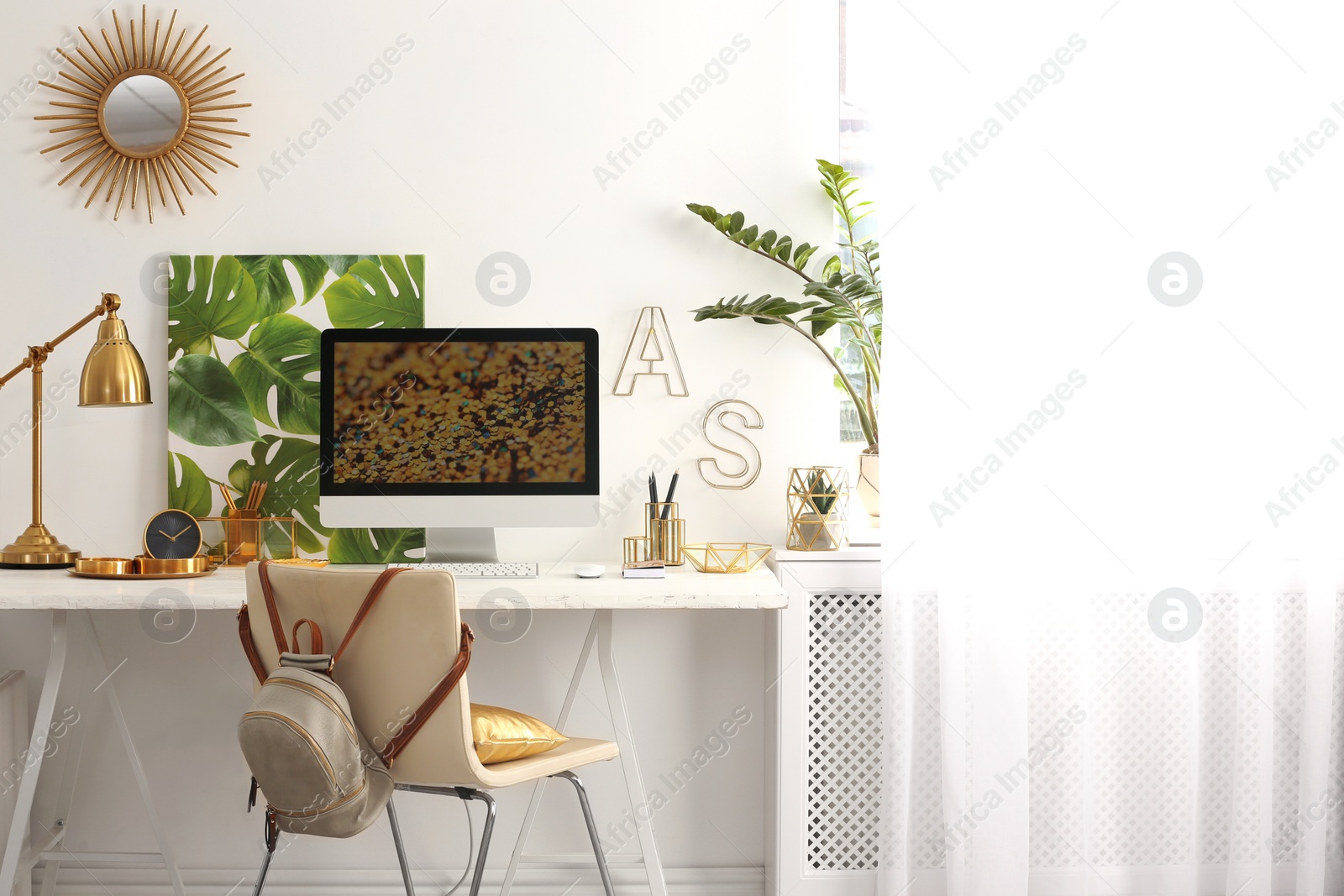 Photo of Modern workplace with computer and golden decor on desk near wall. Stylish interior design