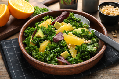 Tasty fresh kale salad on wooden table, closeup