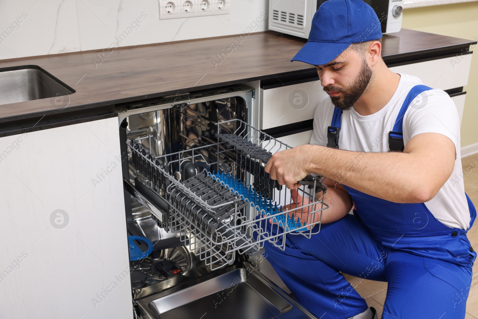 Photo of Serviceman repairing dishwasher cutlery rack in kitchen