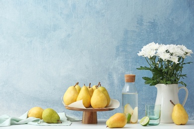 Photo of Stand with fresh ripe pears on table against color background