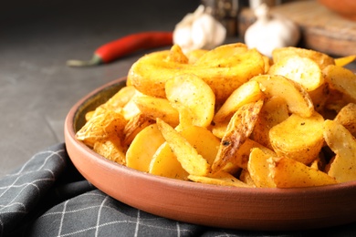 Photo of Plate of delicious oven baked potatoes on table, closeup