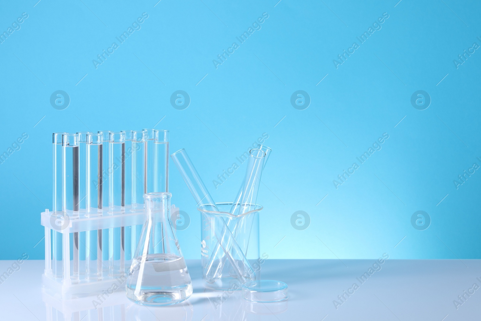 Photo of Laboratory analysis. Different glassware on table against light blue background, space for text