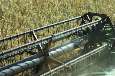 Photo of Modern combine harvester in agricultural field, closeup view of reel