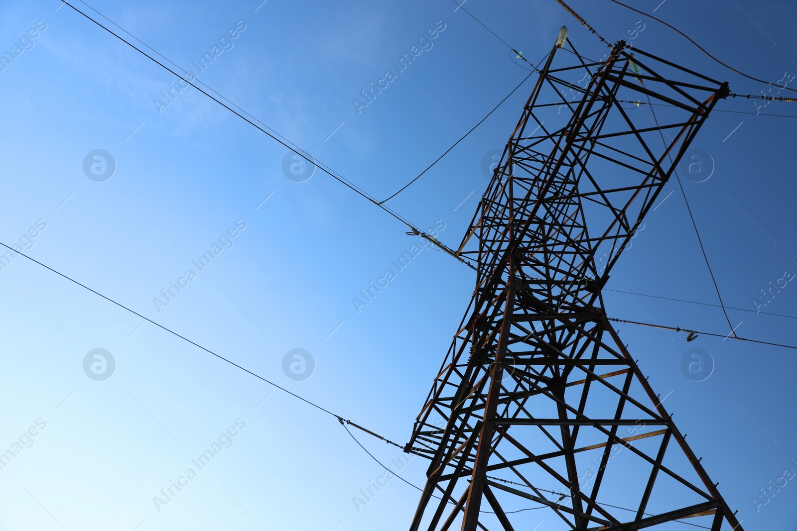 Photo of High voltage tower against beautiful blue sky, low angle view