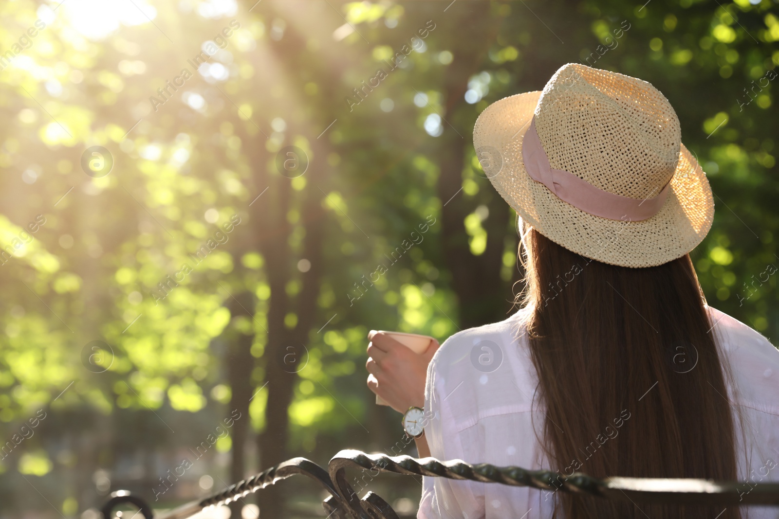 Photo of Woman with drink in park on sunny day, back view. Space for text