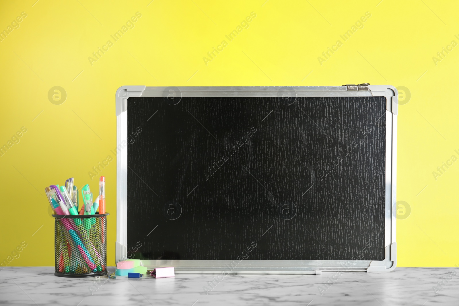 Photo of Small chalkboard and different school stationery on table