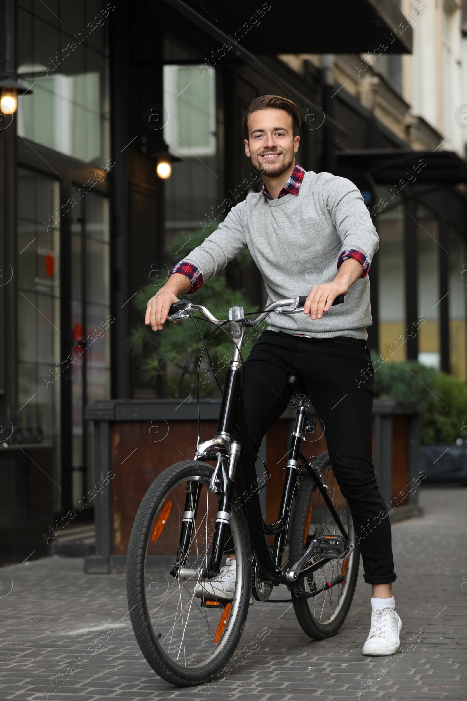 Photo of Handsome happy man riding bicycle on city street