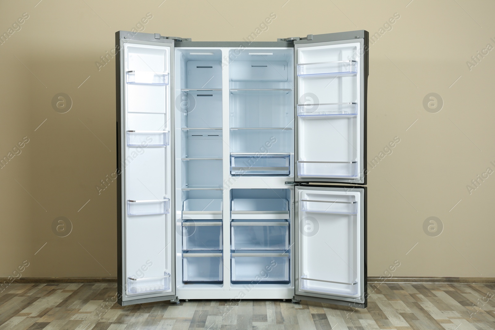 Photo of Modern empty refrigerator near beige wall. Home appliance