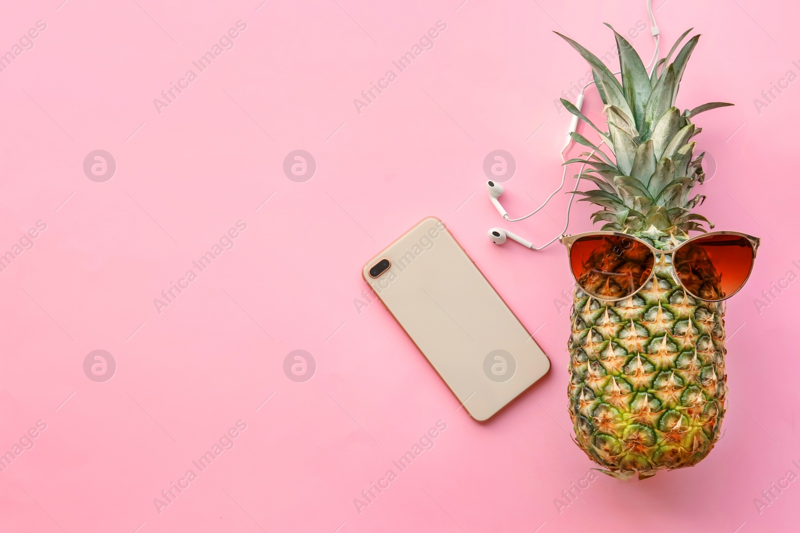 Photo of Fresh ripe pineapple with earphones and mobile phone on color background, top view