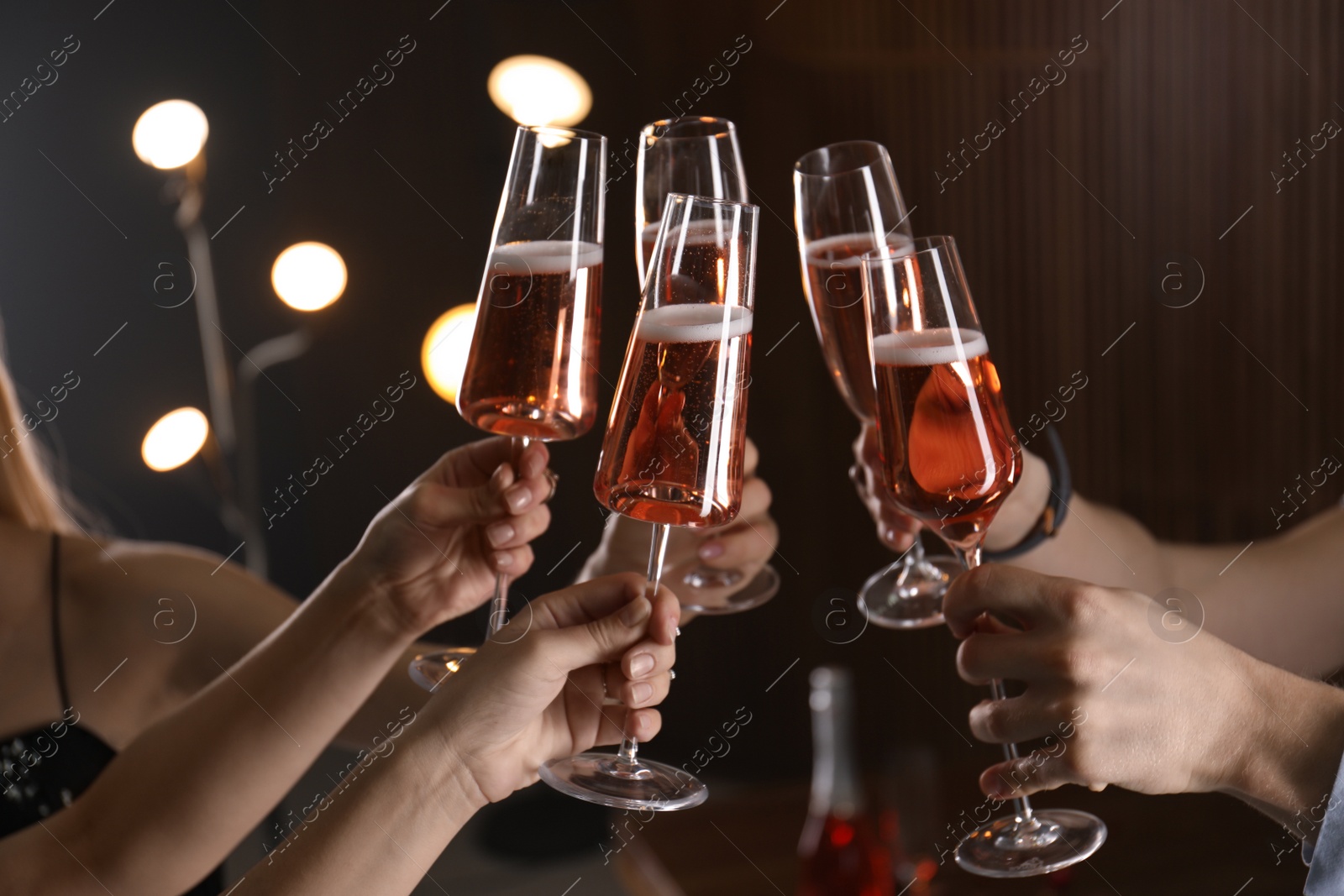 Photo of Friends clinking glasses with champagne on blurred background, closeup