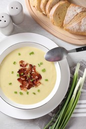 Photo of Tasty potato soup with bacon in bowl served on white wooden table, flat lay