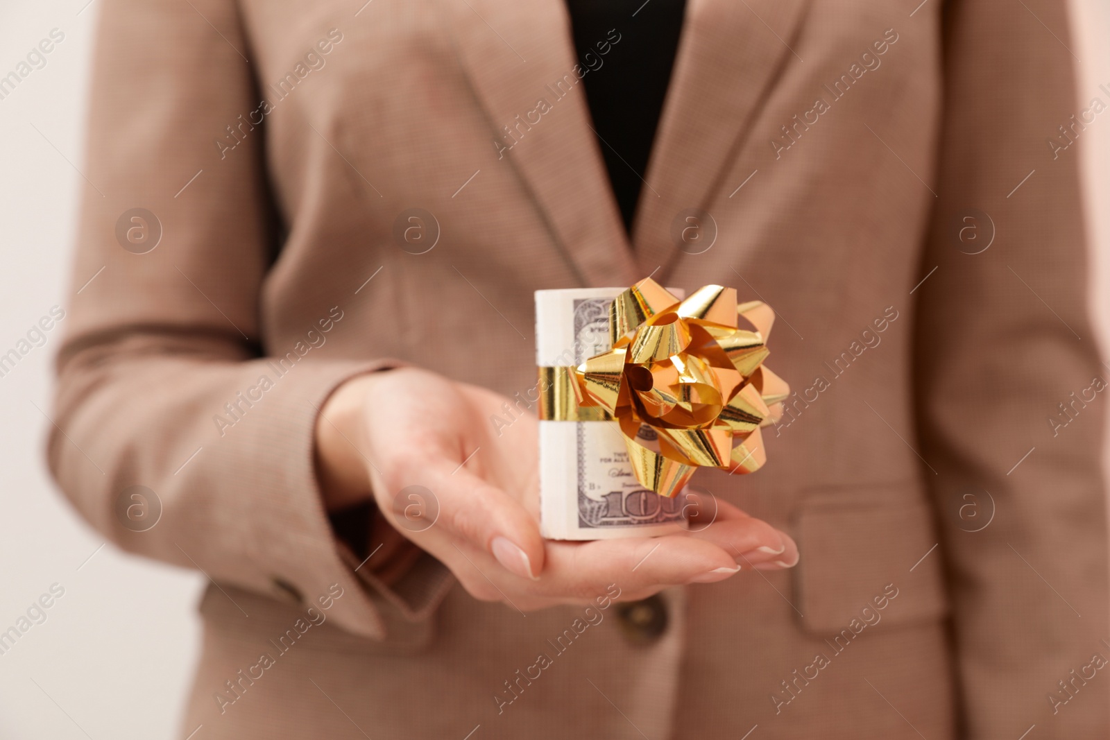 Photo of Woman holding bundle of dollars tied with ribbon, closeup