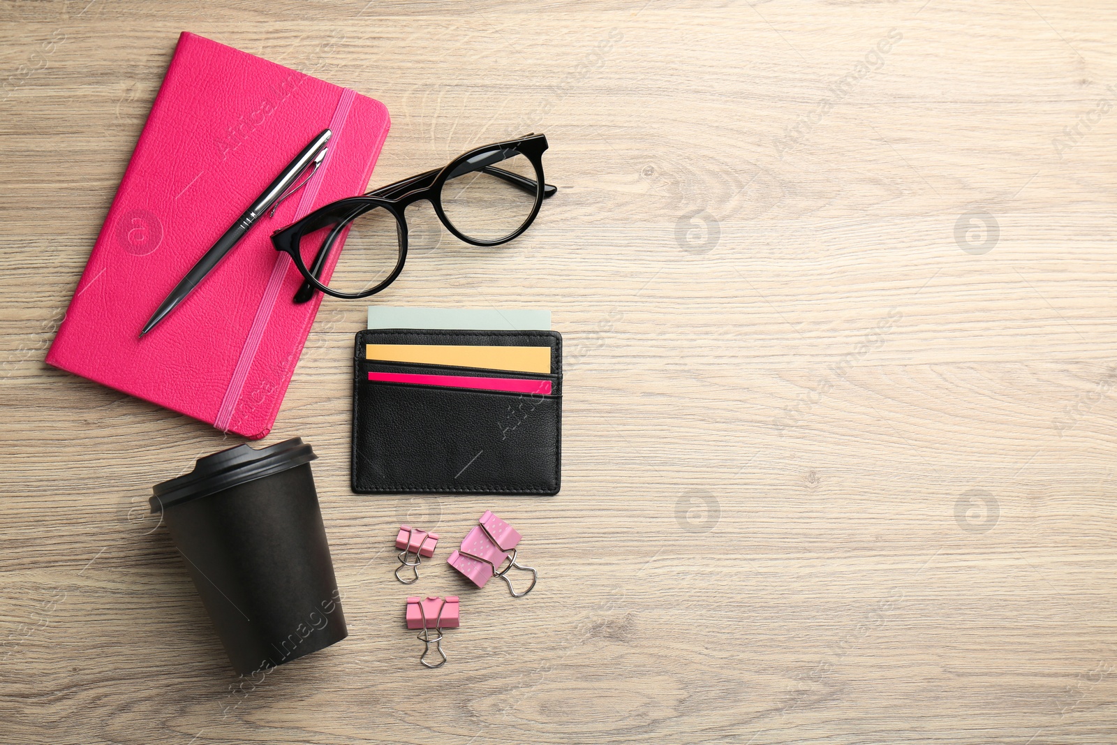 Photo of Leather business card holder with colorful cards, stationery, glasses and coffee on wooden table, flat lay. Space for text