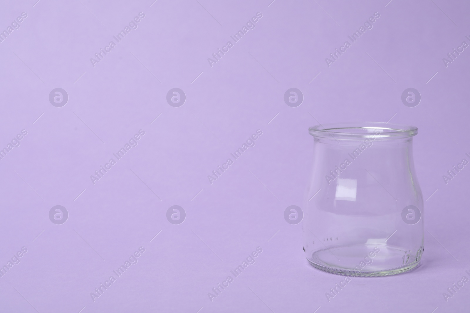 Photo of Open empty glass jar on lilac background, space for text