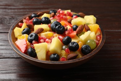 Photo of Delicious fruit salad in bowl on wooden table