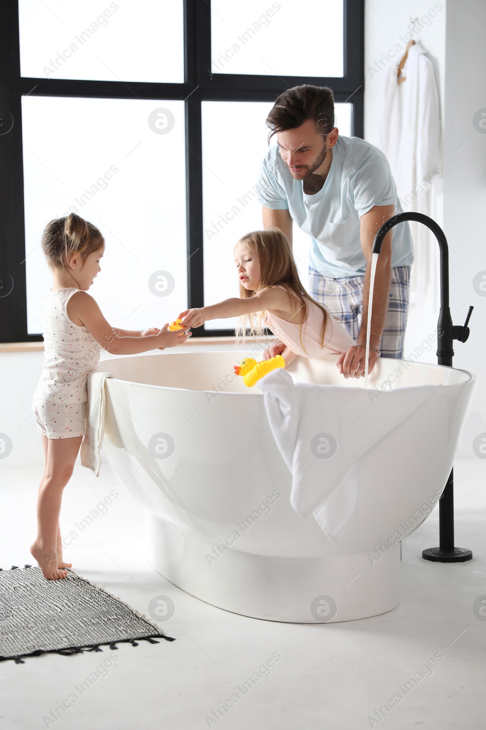 Photo of Young father with little daughters in bathroom